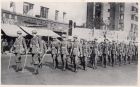 Photograph of soldiers of the 1st Battalion, The Durham Light Infantry, marching through a city street, taken at Shanghai, China, c.1938