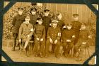 Photograph of a group of medical orderlies from various regiments, including The Durham Light Infantry and The West Yorkshire Regiment, taken at Rennbahn prisoner of war camp, Munster, Germany, endors