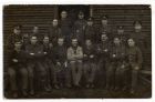 Photograph of a group of Durham Light Infantrymen outside a wooden barracks hut, including Private William Harrington, seated, front row, right, n.d. [1914 - 1916]