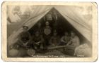 Photograph of seven Durham Light Infantry soldiers in a tent opening, captioned 'the pleasures of camp, 1923', Strensall, Yorkshire, 1923