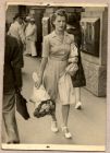 Photograph captioned 'Received in my first letter', showing Mrs Leather walking along a street, holding a bunch of flowers, n.d.