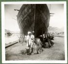 Photograph of a boat being repaired by two men, possibly taken in Aden, c.1941