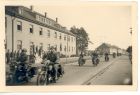 Photograph of soldiers of the 113 Light Anti-Aircraft Regiment, Royal Artillery (Territorial Army), on motorcycles, driving past a saluting base, taken in Germany, 8 May 1945