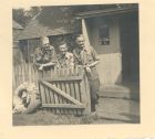 Photograph of Battery Sergeant-Major Stanley Levitt, 113 Light Anti-Aircraft Regiment, Royal Artillery (Territorial Army), left, standing with two soldiers at the gate to an office, taken in Germany, 