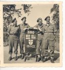 Photograph of four soldiers of the 113 Light Anti-Aircraft Regiment, Royal Artillery (Territorial Army), standing by a direction sign to the 162 Battery office, taken in Germany, June 1945
Left to ri