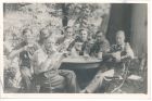 Photograph captioned Even the bottles were slewed!, showing a group of soldiers of the 113 Light Anti-Aircraft Regiment, Royal Artillery (Territorial Army), drinking in a camp, taken in Germany, 1945