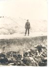 Photograph of a soldier standing next to an open mass grave at Belsen concentration camp, Germany, [April - May] 1945