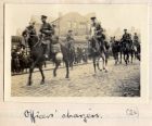 Photograph of horsemen of the 6th Battalion The Durham Light Infantry riding down a street watched by civilians, captioned: Officers' chargers, n.d. [1914 - 1915]