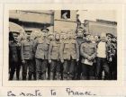 Photograph of a group of soldiers of the 6th Battalion The Durham Light Infantry standing beside a railway engine, captioned: En route to France, n.d. [1915]