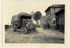 Photograph of a truck in military use in a village street, captioned: St. Jaus-ter-Biezen, Belgium, n.d. [1915]