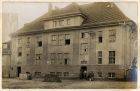 Photograph of barrack building with prisoners in doorway, captioned: V. The cook-house, also (later) the theatre, entrance to baths on extreme left, Graudenz, West Prussia, Germany, October 1918