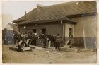 Photograph of a camp building with prisoners and German soldiers, captioned: VIII.Outside the tin rooms, German orderlies enlarging the lockers, here all parcels were stacked and issued and tins store